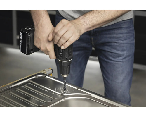 Muž vrtá do dřezu akumulátorovým vrtacím šroubovákem