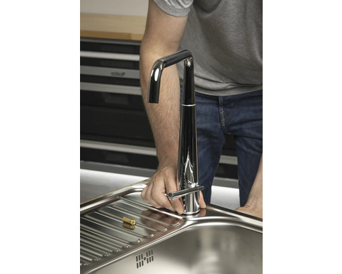 Muž instaluje vodovodní kohoutek do dřezu.