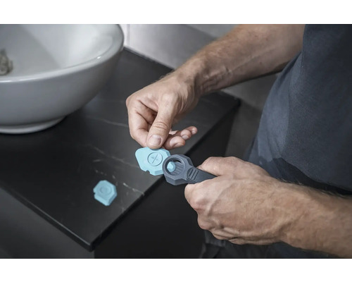 Muž používá spárovací nástroj v koupelně na silikonové spáry.