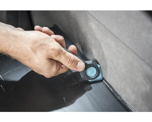 Ruka používá nástroj pro vyhlazování spár k vyhlazení spár mezi dlaždicemi.