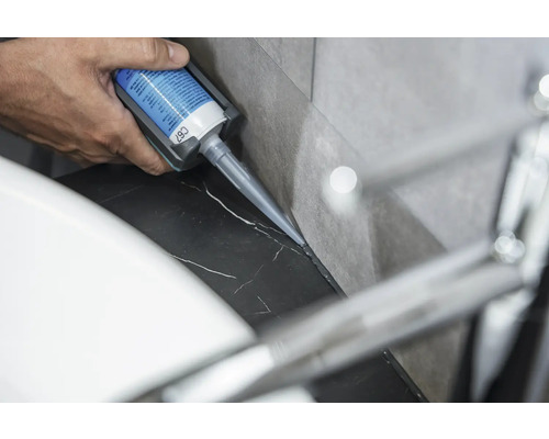 Osoba nanáší silikon na mramorový povrch.