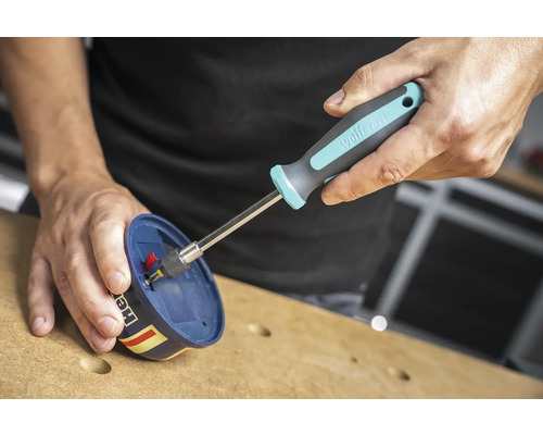 Osoba používá šroubovák k utažení šroubu.