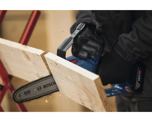 Akumulátorová řetězová pila řeže dřevěnou desku. Logo společnosti Bosch.