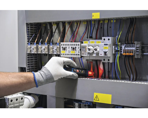 Elektrikář kontroluje rozvaděč pomocí zkoušečky napětí
