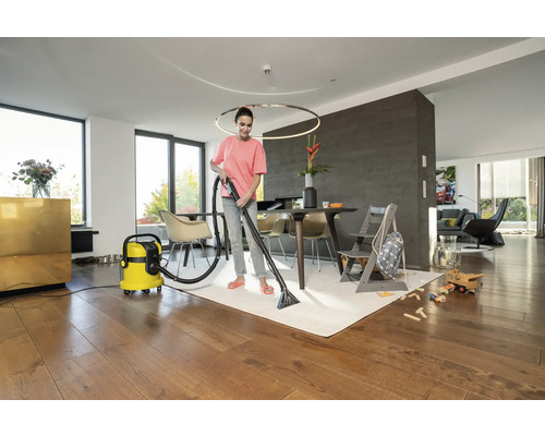 Žena čistí koberec pomocí čisticího vysavače v obývacím pokoji