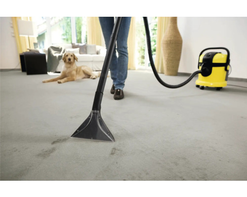 Osoba čistí koberec čisticím vysavačem v jasném obytném prostředí