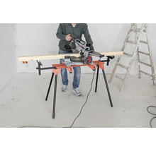 Osoba obsluhuje pokosovou pilu na řezacím stole vedle žebříku.