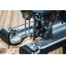 Detailní záběr na přímočarou pilu řezající dřevo.