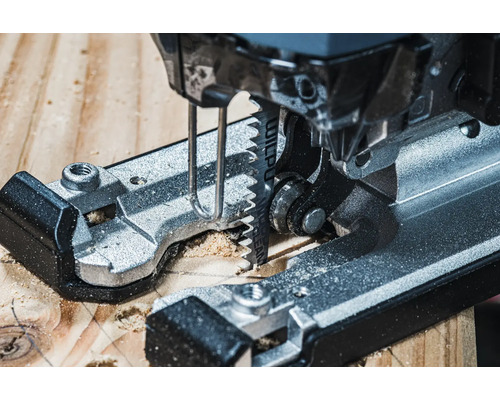 Detailní záběr na přímočarou pilu řezající dřevo.