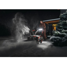 Osoba používá sněhovou frézu k odklízení sněhu.