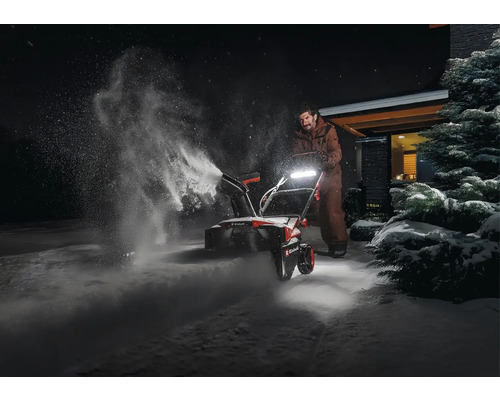 Osoba používá sněhovou frézu k odklízení sněhu.