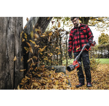 Muž s akumulátorovým foukačem listí na zahradě fouká listí