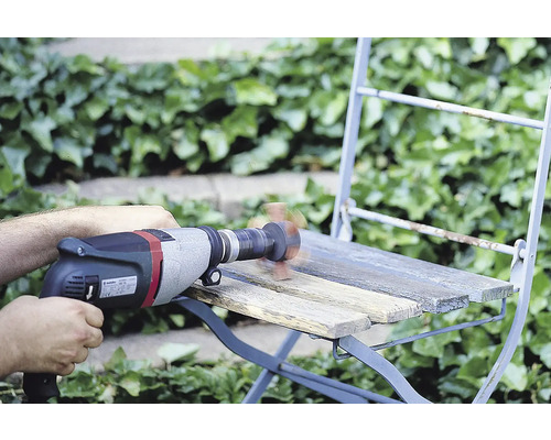 Řemeslník brousí dřevěnou židli s vrtačkou a brusným nástavcem venku.