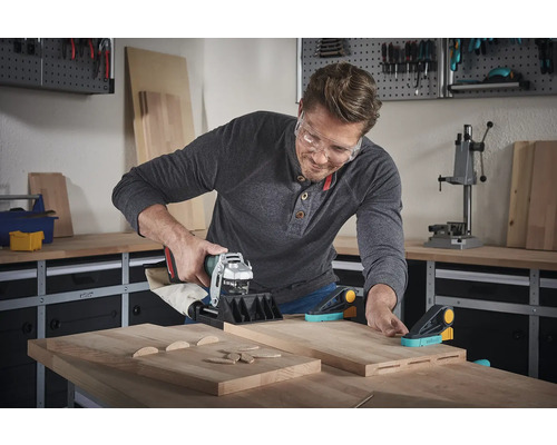 Muž používá kolíkovač v dílně k obrábění dřevěných dílů.