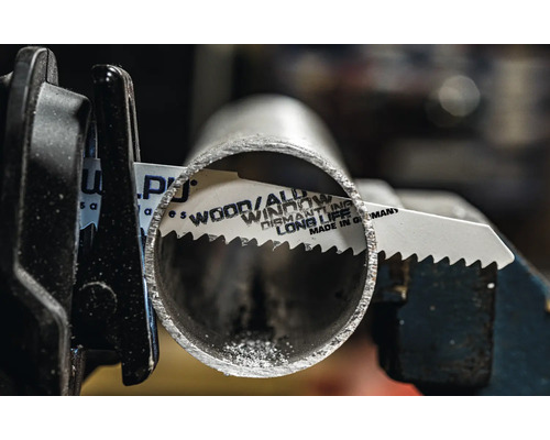 Pilový list na kov řeže kovovou trubku v držáku