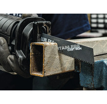 Pila ocaska řeže kovovou trubku ve svěráku.