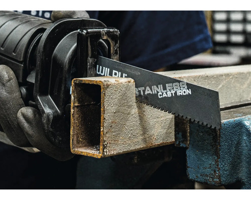 Pila ocaska řeže kovovou trubku ve svěráku.