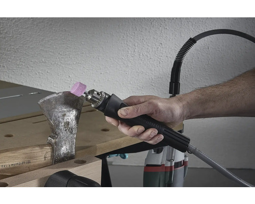 Osoba brousí sekeru pomocí brusného nástroje.