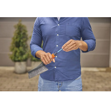 Osoba připojuje kartáč k zahradní hadici