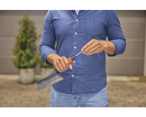 Osoba připojuje kartáč k zahradní hadici