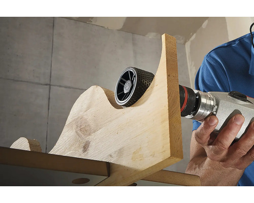 Rotační rašple používaná na kusu dřeva s vrtačkou.