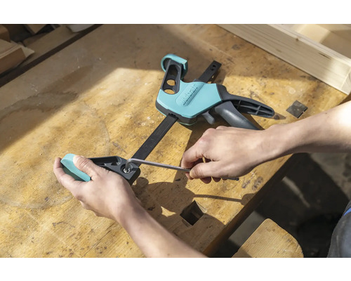 Osoba nastavuje svěrku jednou rukou pomocí imbusového klíče na pracovním stole.