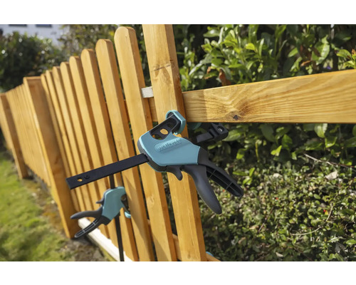 Dřevěný plot upevněný jednou rukou svorkami Wolfcraft