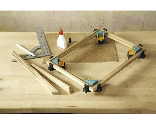 Pracovní stůl s pokosovou svorkou, dřevěné lamely, úhelník, tužka a láhev lepidla na zpracování dřeva