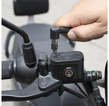 Osoba používá šroubovák s úhlovým nástavcem k práci na motocyklu.