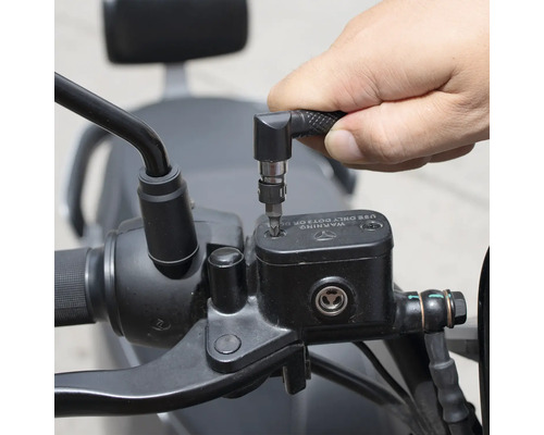 Osoba používá šroubovák s úhlovým nástavcem k práci na motocyklu.