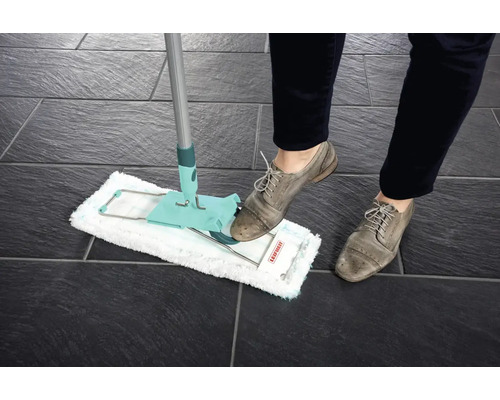 Mop v akci na tmavé dlažbě, ovládaný osobou v botách.