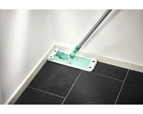 Mop na tmavé dlažbě u bílé stěny