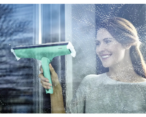 Žena čistí okna stěrkou na okna