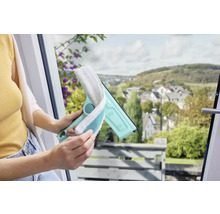 Žena používá stěrku na okna s návlekem z mikrovlákna k čištění okna