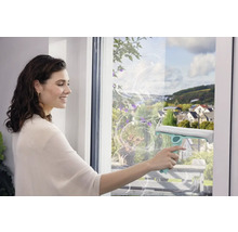 Žena čistí okna stěrkou pro čištění beze šmouh