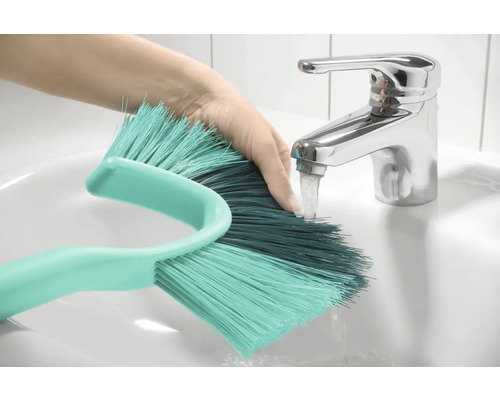 Ruka pod kohoutkem oplachuje kartáč v umyvadle