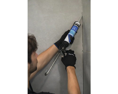 Řemeslník nanáší tmel na spáru dlaždice