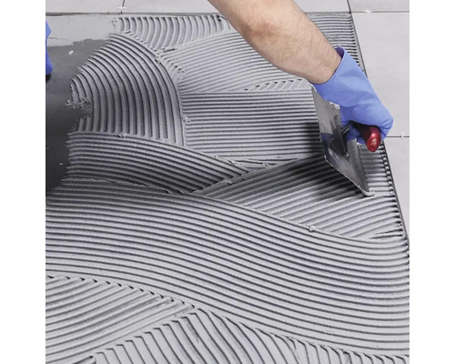 Obkladač nanáší lepidlo na dlaždice na podlahu