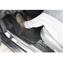 Interiér vozidla s podlahovou rohoží a nohou na pedálu