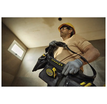 Řemeslník s brašnou na nářadí Stanley a svinovacím metrem na staveništi