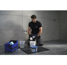 Obkladač pracuje s cementovou spárovací hmotou Ceresit v koupelně