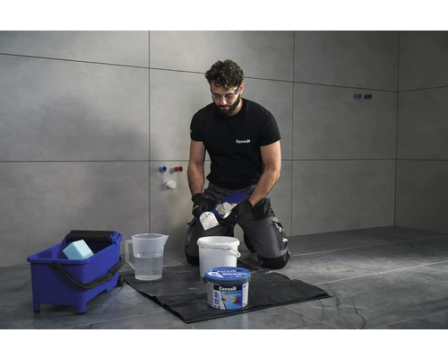 Obkladač pracuje s cementovou spárovací hmotou Ceresit v koupelně