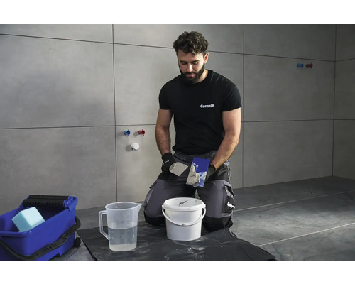 Obkladač při práci s nářadím a materiály pro obkládání.