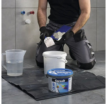 Obkladač připravuje spárovací hmotu s nářadím a spárovací hmotou Ceresit CE 40 Premium