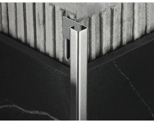 Detailní záběr kovové dlaždicové lišty v rohu mezi dvěma dlaždicemi