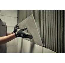 Dlaždič instaluje obklad v koupelně