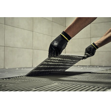 Obkladač pokládá dlaždice pomocí speciálního nářadí a ochranného oděvu.