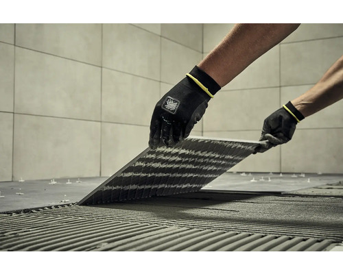 Obkladač pokládá dlaždice pomocí speciálního nářadí a ochranného oděvu.