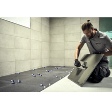 Dlaždič při práci, dlaždice, nářadí a logo AkKit