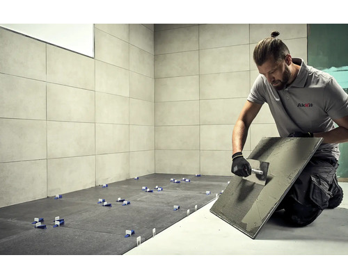 Dlaždič při práci, dlaždice, nářadí a logo AkKit